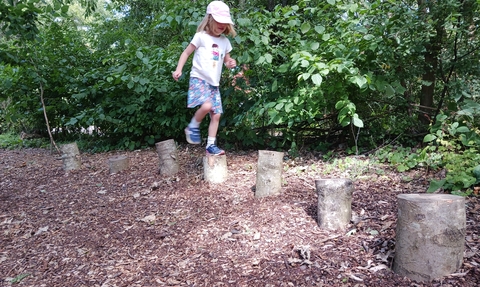 Child hopping on wooden logs at a kent wildlife trust forest school experience day